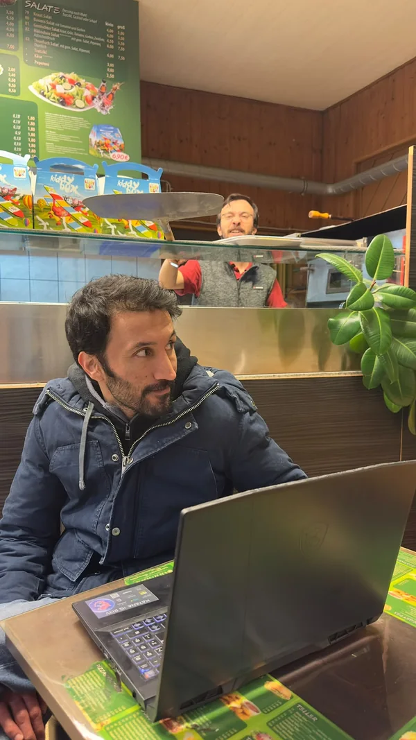 Ein Gast mit Laptop und ein Mitarbeiter hinter der Theke